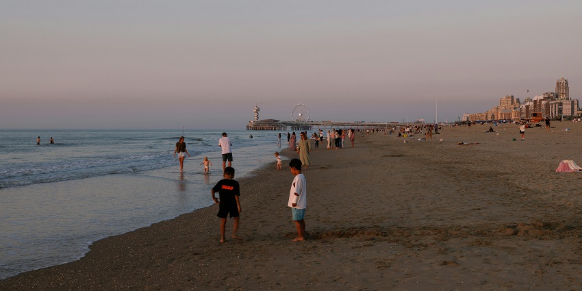 An evening on a beach with people enjoying the relaxed waves with their loved ones.
