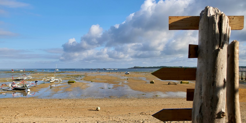 Picturesque view of beach in Sanur during day time with clear blue water, blue sky and golden sand