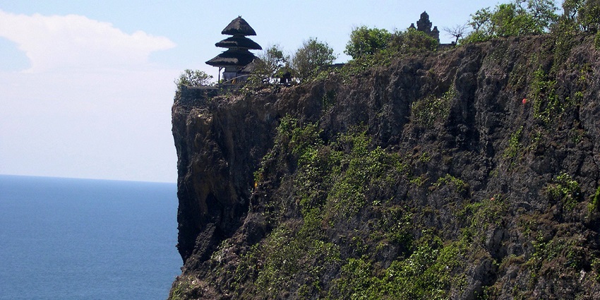 An image showing a cliff near the ocean with waves in the background at Uluwatu Temple