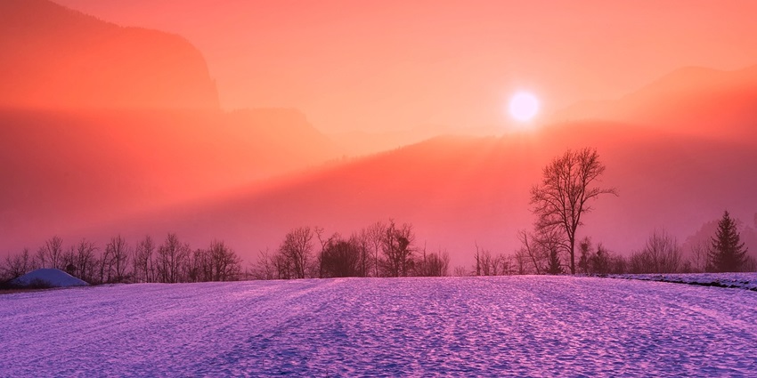 Stunning winter sunrise illuminating the snow-covered landscape with warm hues.