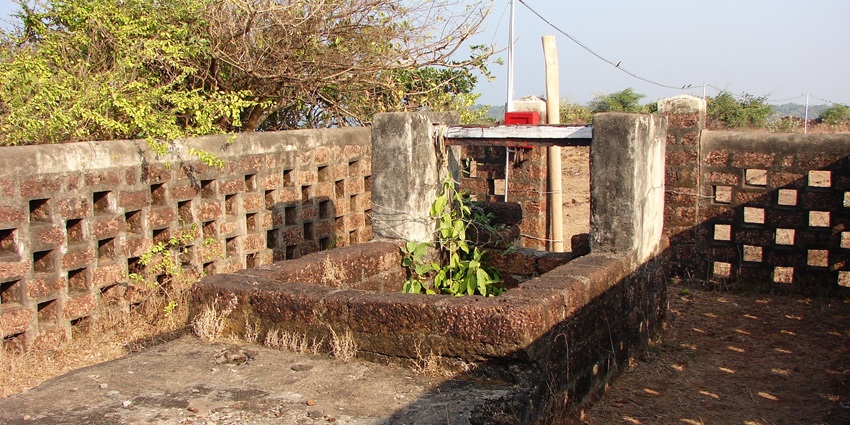 An image of the ancient well at Devgad Fort surrounded by stone walls and lush greenery