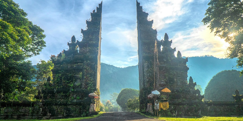 A woman in a white dress walking up the stone stairs of Lempuyang temple.