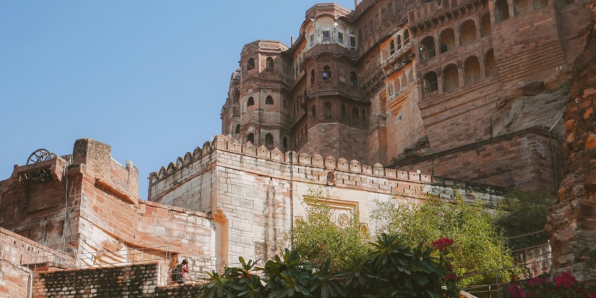 View of tall fort walls adorned with intricate architecture and lush shrubs