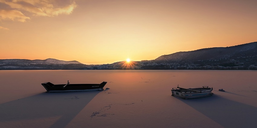 A stunning winter sunset illuminating boats on the water, creating a peaceful scene.