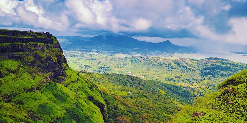 A serene view of lush green hills landscape with clear blue sky and white clouds
