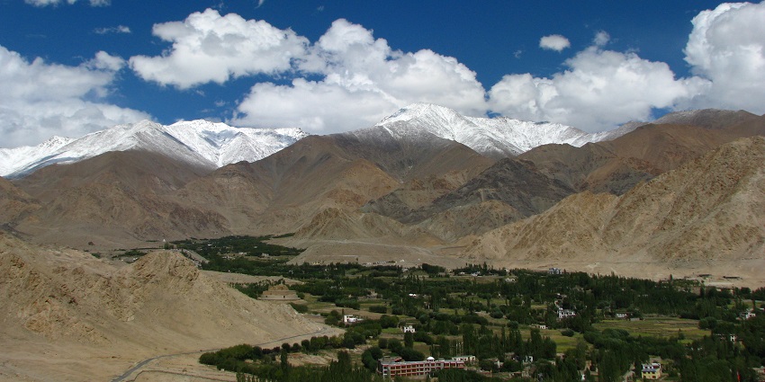 Picturesque view of a mountains and lush green trees under white clouds and blue sky