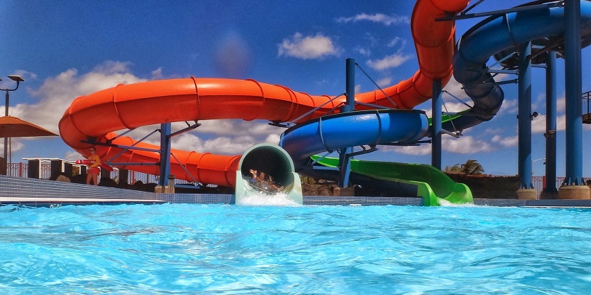 An image of a large pool with a spiral water slide going down to it offering ultimate fun.
