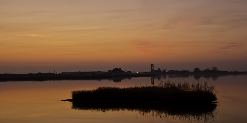 The scenic view of a beautiful sunset over a lake with orange hues.