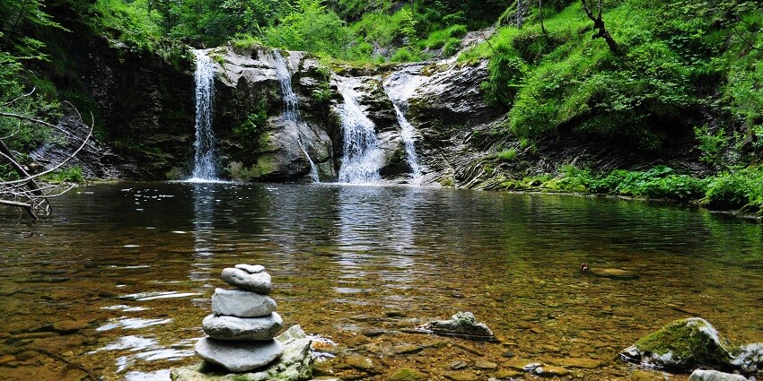 A picture of Amboli waterfall gushing down the rocks and is surrounded by lush landscapes