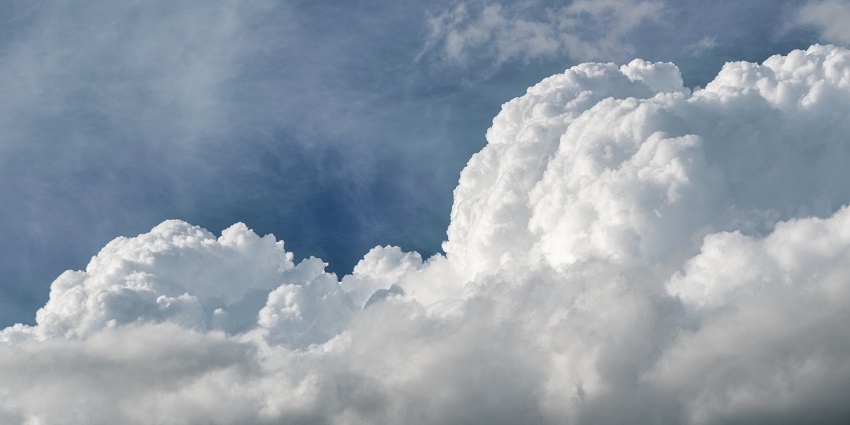 Fluffy cumulus clouds scattered across a bright blue sky on a sunny day.