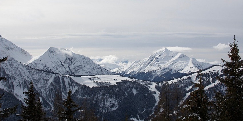 Snow-capped mountain peaks rise majestically against a clear blue sky, showcasing nature's vegetation.