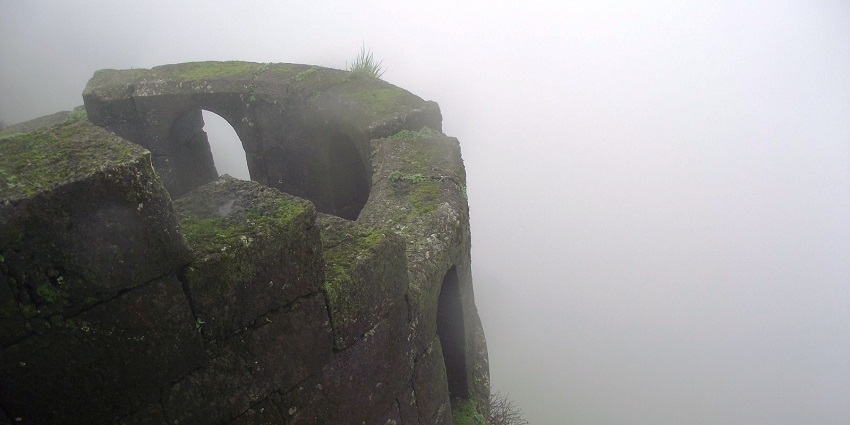 Visapur Fort in Maharashtra, India, surrounded by lush greenery and cloudy skies.