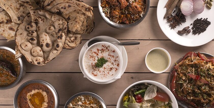 An Indian food spread consisting of a variety of curries, salad, curd, and flatbread.