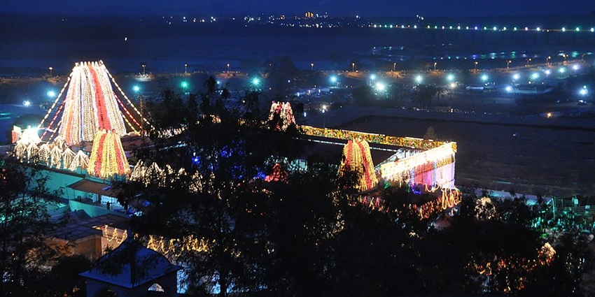 A night view of Bhadrachalam Temple, with multiple gopurams illuminated by lights.