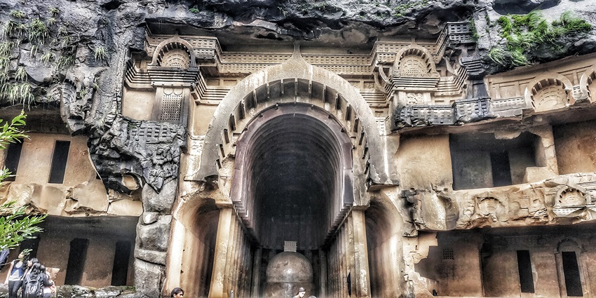 A frontal view of the entrance of a massive cave system in Maharashtra with intricate wall carvings