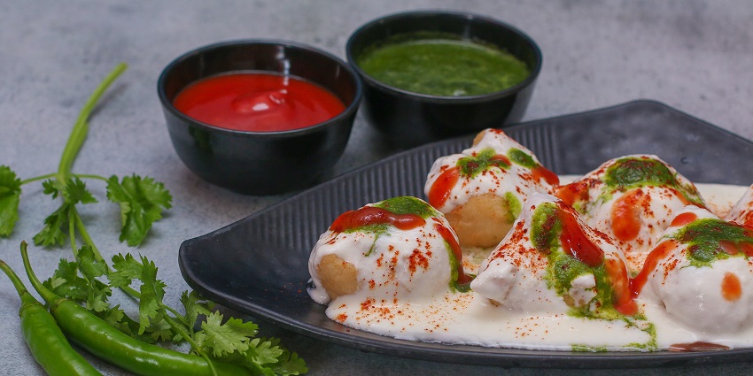 Lentil fritters served on a plate topped with creamy yoghourt, green and red dip