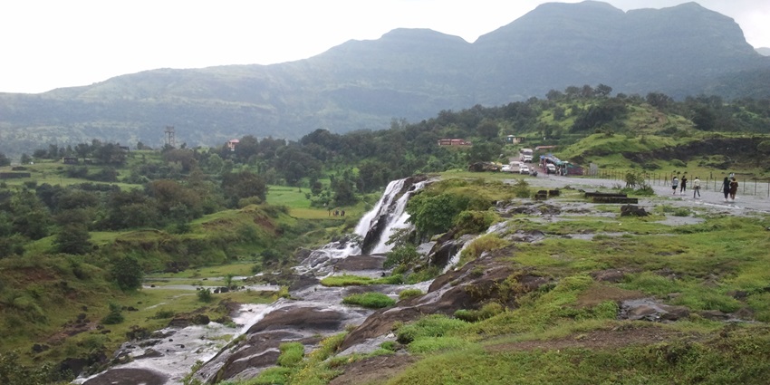 A picture of a scenic plateau area in Maharashtra with a small waterfall, surrounded by lush greenery