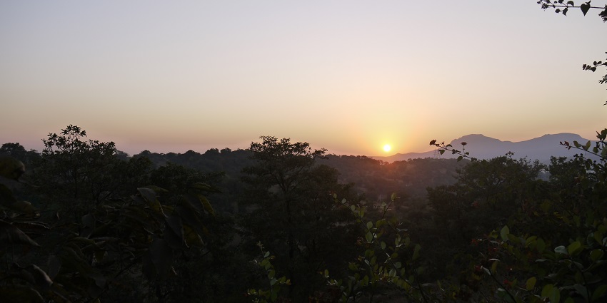 A breathtaking sunrise view over the serene waters of Bhandardara, surrounded by hills.