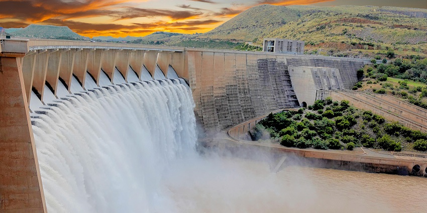 A scenic view of a large water dam surrounded by lush green hills, captured during the daytime.