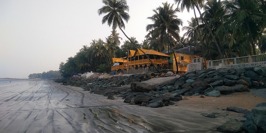 A calm view of Bhayander Beach with boats lined along the shore against the sunset.