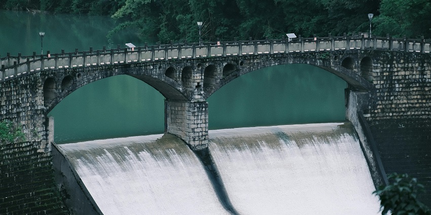 A scenic view of Bhimgarh Sanjay Sarovar Dam, reflecting hills and trees
