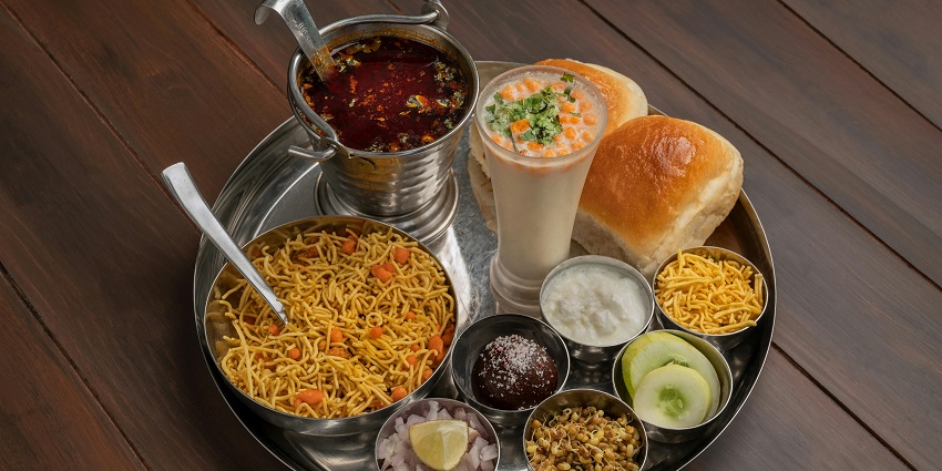 A platter with various dishes and accompaniments is placed alongside a beverage