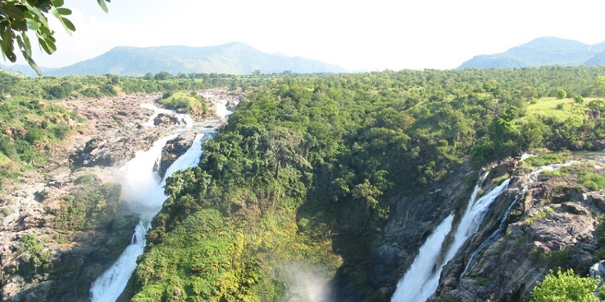 An aerial view of two waterfalls flowing down from a hill and being submerged into one