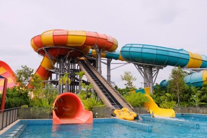 The image shows a yellow water slide curving downward into a clear blue pool in Bhor Adventure Park.