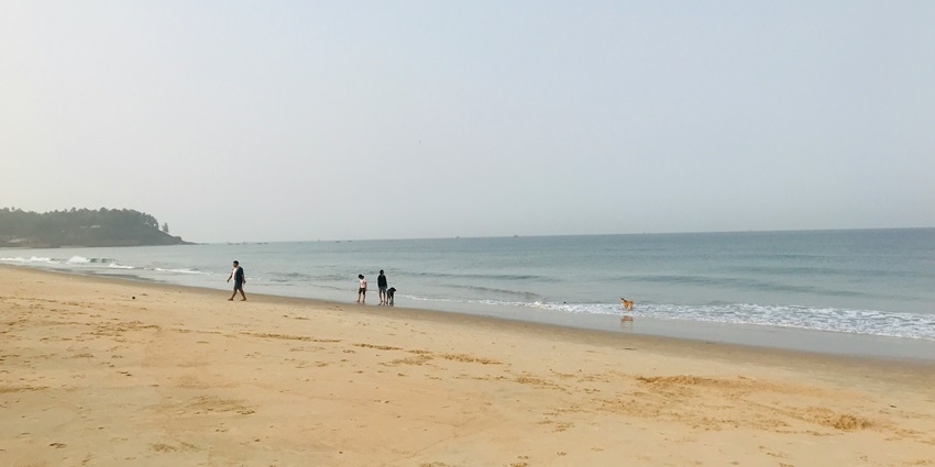 Image of a beach with people strolling around, similar to the Bhuigaon beach in Vasai
