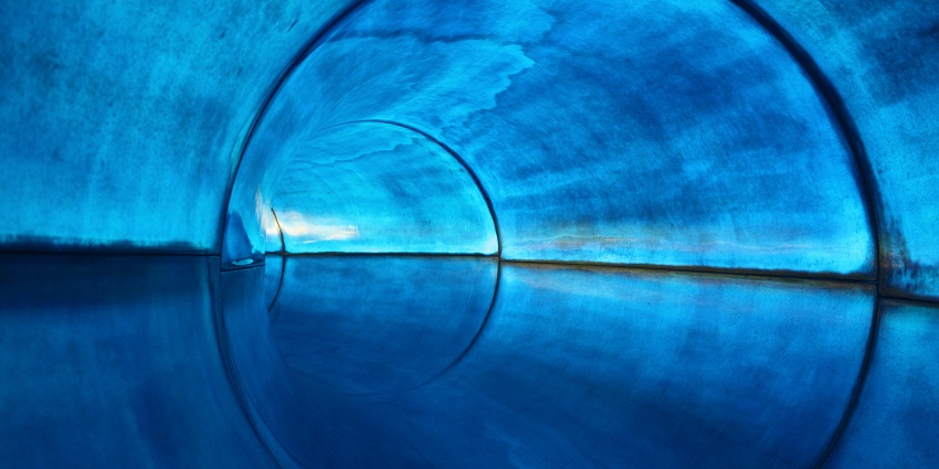 A blue waterslide into a swimming pool, akin to slides.