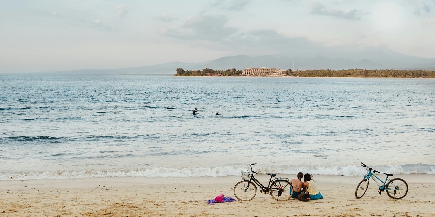 A picture of two people sitting on the shore of the Gili islands during the time of the sunset.