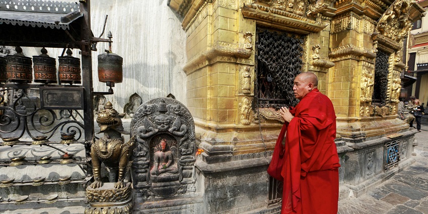 A serene monk meditating beside a stunning Buddha figurine, radiating peace.