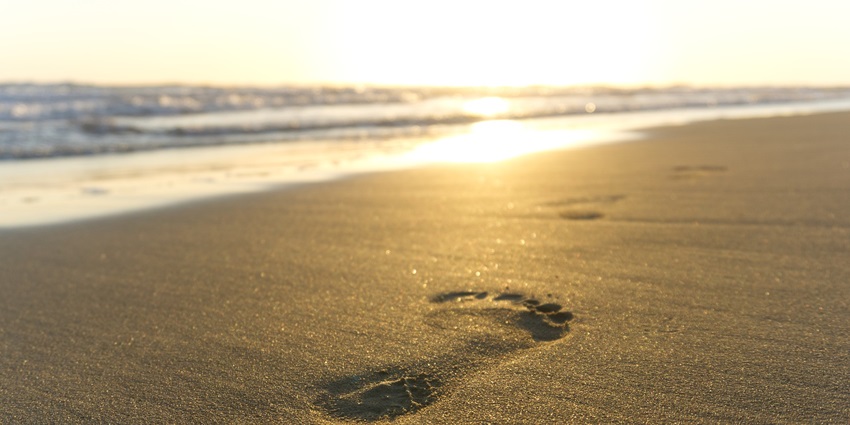 A view of the Byndoor Beach at sunset, with the sun setting over the horizon.