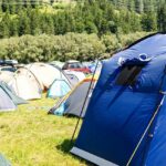 Single white camp setup amongst the backdrop of the green hills around.