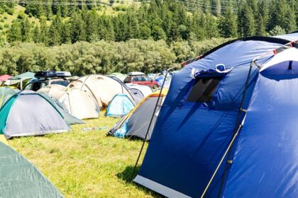 Single white camp setup amongst the backdrop of the green hills around.