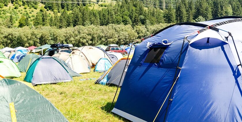 Single white camp setup amongst the backdrop of the green hills around.