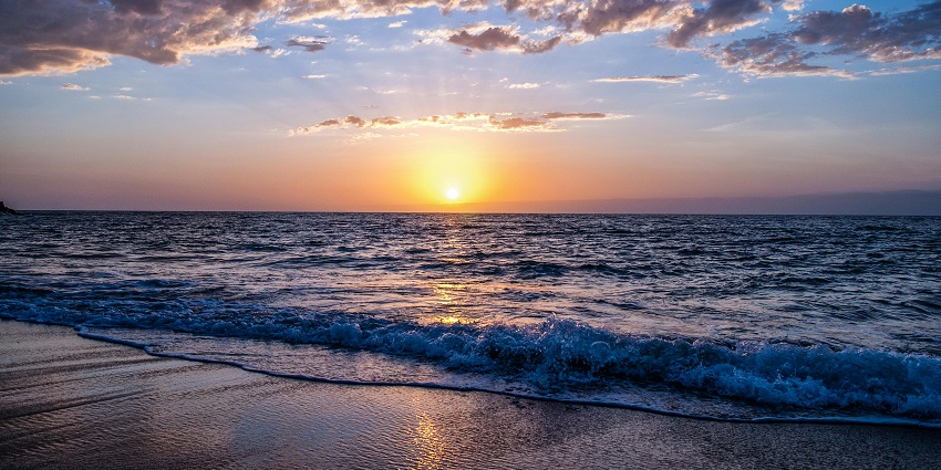 view of the sun setting at the horizon of the beach spreading vibrant hues in the sky