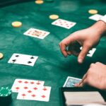 A glimpse of a person shuffling a deck of cards and displaying it on the green table.