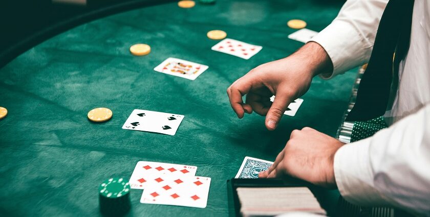 A glimpse of a person shuffling a deck of cards and displaying it on the green table.