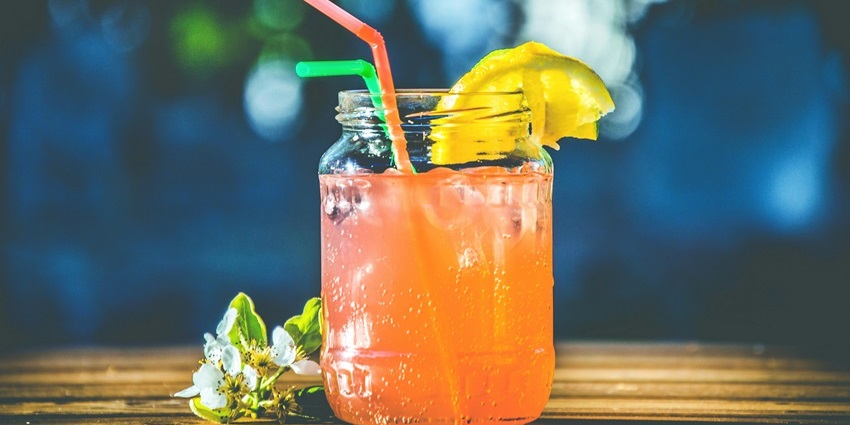 Image of a pink drink in a glass with green and red straw served in a restaurant