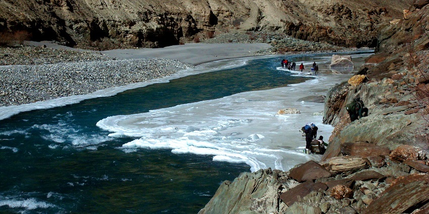 An enchanting view of majestic mountains, snow-clad grounds, and shimmering waters.