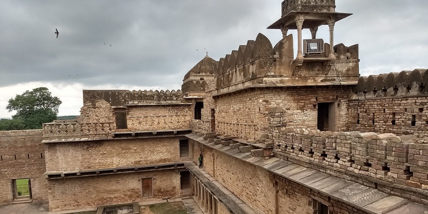 A scenic view of Chanderi Fort surrounded by lush greenery and historic architecture.