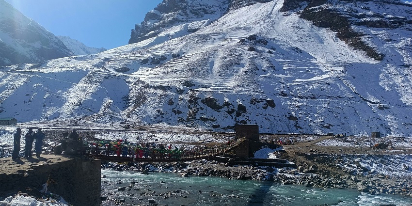 Snow-covered mountain with a bridge over a river, ideal for road trips from Chandigarh.