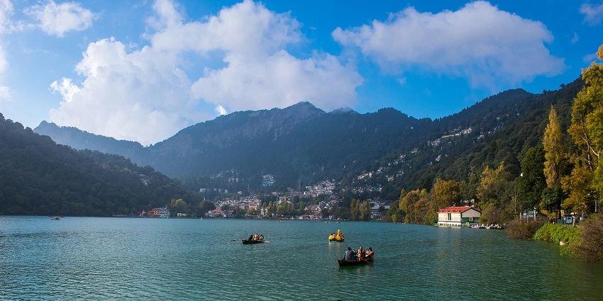 A group of people rowing their boats amidst the dreamy Nainital Lake, surrounded by mountains.