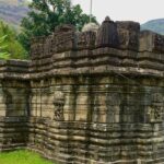 Image of Kukadeshwar Temple at Chavand with scattered stone structures and walls.