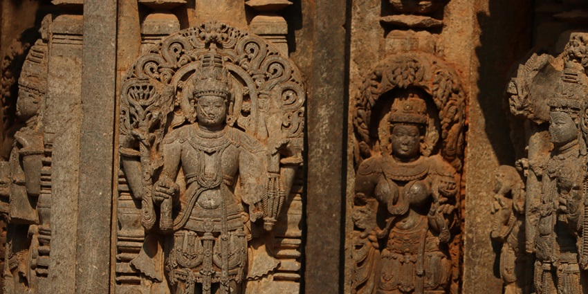 Ancient rock-cut sculptures carved into a cave wall with detailed artistic designs.