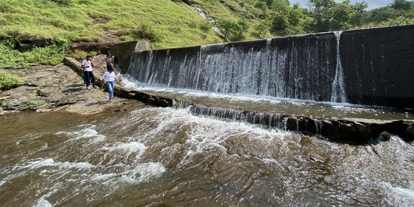 A picture of a small dam in a scenic hill station near Nagpur, with water pouring down into a river