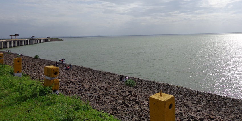 Image of a water body in day time with people on its shore, resembling Chikloli Dam