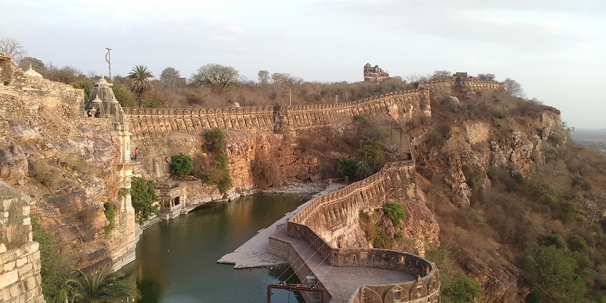A view of calm river waters running through the stone walls of the historic Chittor Fort.
