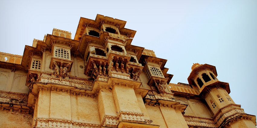 Udaipur City Palace with ornate balconies and windows, overlooking Lake Pichola.
